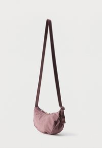 Μικρή τσαντάκι ώμου σε σχήμα ημισελήνου, μωβ, με ρυθμιζόμενο λουρί και κλείσιμο με φερμουάρ στην κορυφή, παρουσιάζεται σε απλό λευκό φόντο.