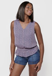 Mouwloos topje in een roze en blauwe bloemenprint, met een V-hals en een relaxte pasvorm, gecombineerd met denim shorts. Soepele stoftextuur.