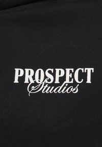 Tessuto nero con una trama liscia che presenta la scritta "PROSPECT" in lettere bianche in grassetto e "Studios" in uno stile corsivo sottostante.
