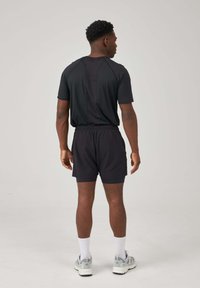 Men's activewear set in black, featuring a short-sleeve shirt and elastic waistband shorts, both made from lightweight, breathable fabric.