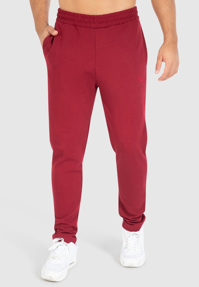 Bordeaux joggerbroeken van zachte stof, met een elastische tailleband, zijzakken en een slanke pasvorm, gecombineerd met witte sneakers.