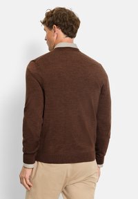 Brauner gestrickter Pullover mit geripptem Saum und Händen, der einen hellen Kragen hat. Die Textur wirkt weich und warm.