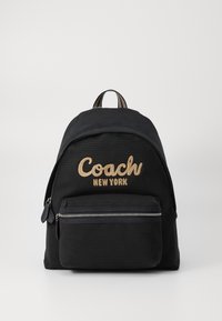 Fekete szövet hátizsák, lekerekített formával, arany "Coach New York" felirattal, elülső cipzáras zsebbel és felső hordozó fogantyúval.