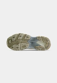 Shoe sole with a textured pattern, featuring a mix of beige and grey rubber. Distinctive grooves and traction elements for grip.