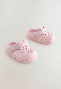 Rozā gumijas kokaši ir ar loku uz siksniņas, perforētu augšdaļu ventilācijai un "BAKER by TED BAKER" iepresēšanu uz zoles.