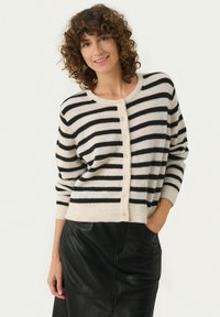 Gestreepte cardigan in crèmekleurige en zwarte wolmix, met een ronde halslijn, knoopsluiting en lange mouwen, gecombineerd met een zwarte leren rok.