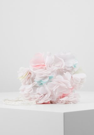 Pochette décorée de fleurs en tissu superposées de couleur pastel rose, blanc et bleu clair, posée sur une surface blanche.