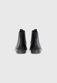 Bottes Chelsea noires en cuir avec une finition texturée, des panneaux latéraux élastiques et des languettes. Dotées d'une semelle en caoutchouc avec des rainures discrètes.