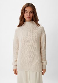 Beige gestrickter Pullover mit hochgeschlossenem Kragen, geripptem Saum und Bündchen, der ein diagonales Texturmuster und einen lässigen Schnitt aufweist.