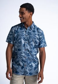 Camisa de botones de manga corta en azul con un patrón floral en azul oscuro, con una tela texturizada y botones marrones en la parte delantera.