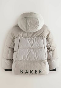 Puffjakke i lys grå, med hætte, quilteafsnit og en fremtrædende "BAKER" tekst detalje på bagsiden nær kanten.