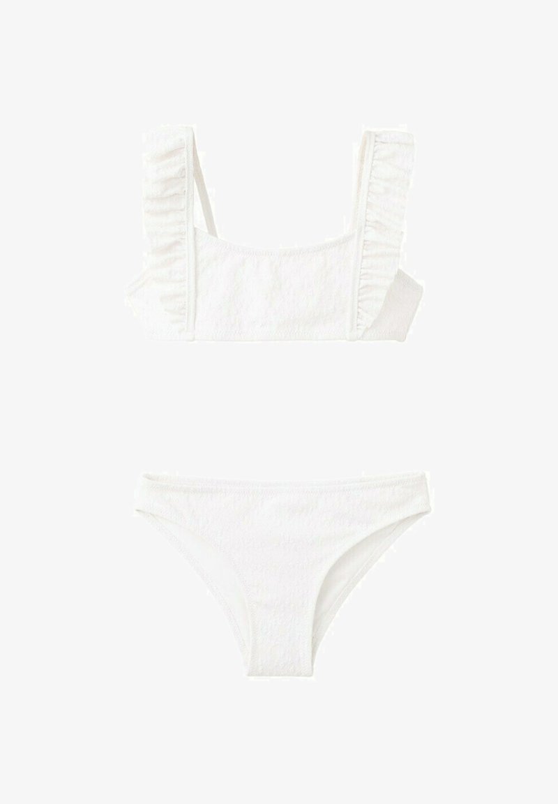 Maillot de bain deux pièces blanc avec bretelles à volants sur le haut et bas uni assorti, posé à plat sur un fond blanc.