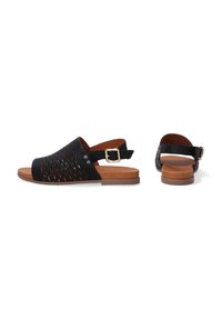Zwarte, geperforeerde leren sandalen met een slingback ontwerp, een gespsluiting en een bruine loopzool. Platte hak, open teen en minimalistische stijl.