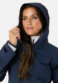 Navy waterproof jacket with a hood, featuring a zippered front, adjustable drawstrings, and a logo embroidered on the chest.