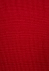 Tessuto a maglia rosso con un pattern strutturato a coste. La superficie è liscia, di colore uniforme e presenta cuciture fini e costanti.