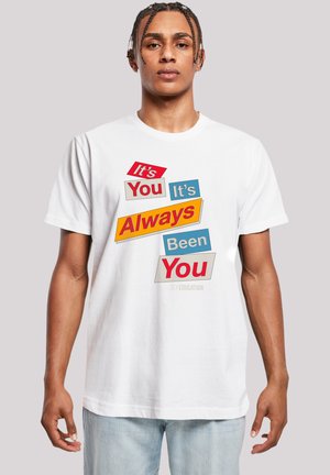 White cotton t-shirt featuring multicolored text. Front graphic includes phrases "It's You," "It's Always Been You," and "Sex Education."