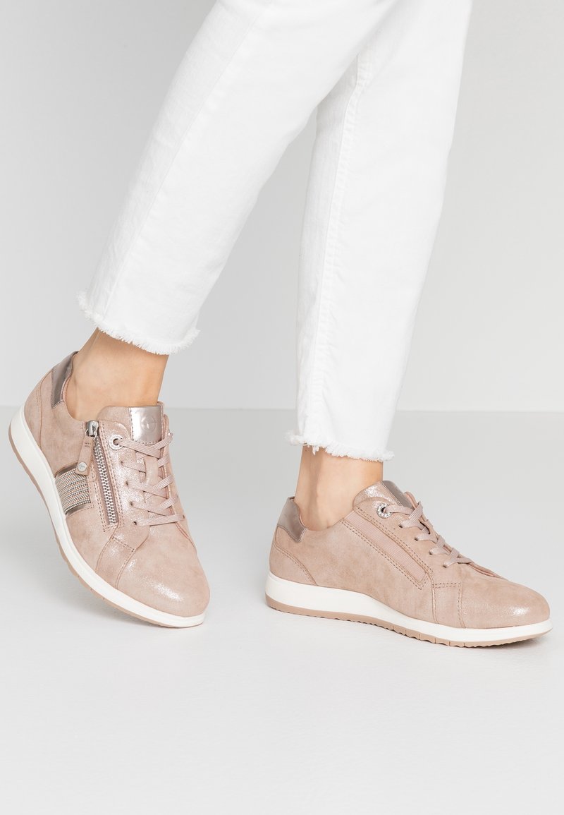 Sneaker in suede rosa chiaro con un accento lucido, caratterizzate da un design con lacci, cerniera laterale e suole in gomma bianca. Indossate con jeans bianchi a vita corta.