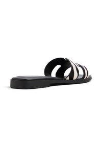 Sandales noires à glisser avec un dessus texturé présentant des rayures noires et blanches alternées, semelle plate et design ouvert sur les côtés.