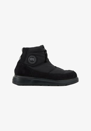 Botte d'hiver noire mi-haute avec tige rembourrée, bout rond, fermeture éclair et écusson circulaire du logo Canada Goose sur le côté.