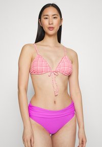 Top de biquíni triangular em gingham rosa com laço na frente, combinado com parte debaixo roxa de cintura alta. Textura suave, alças ajustáveis, design justo.