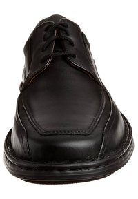 Zapato de vestir para hombre en cuero negro, con punta redondeada, cierre con cordones y costuras visibles a lo largo de la suela y los paneles superiores.
