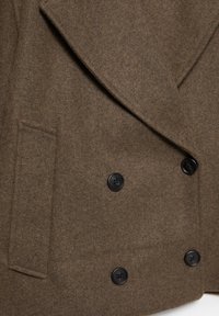 Manteau en mélange de laine brun avec un design croisé, boutons noirs et une poche latérale. Texture douce avec une finition moderne.