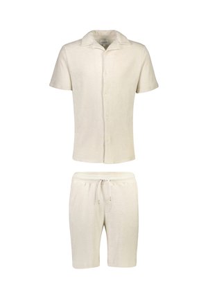Camicia beige a maniche corte con bottoni abbinata a pantaloncini con coulisse realizzati in tessuto morbido e strutturato.