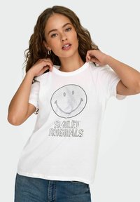 Balta medvilninė marškinėliai trumpomis rankovėmis, su dideliu juodu šypsenėle grafiniu atvaizdu ir tekstu "Smiley Originals" drąsiu, laisvalaikio stiliaus šriftu.