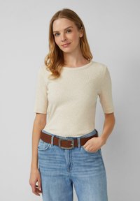 Lichtbeige geribde t-shirt met een ronde hals en korte mouwen, gecombineerd met lichtblauwe denim jeans en een bruin leren riem met een metalen gesp.