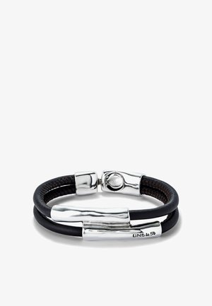 Pulsera de cuero negro con detalles en metal plateado retorcido, con un cierre y una marca grabada. Las bandas dobles crean un efecto de capas.