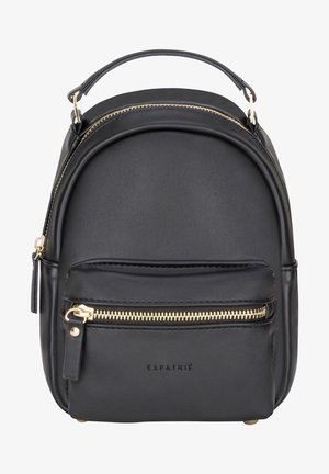 Mini sac à dos en cuir synthétique noir avec fermetures éclair dorées, poche avant, poignée supérieure, et "EXPATRIÉ" embossé sur le devant.