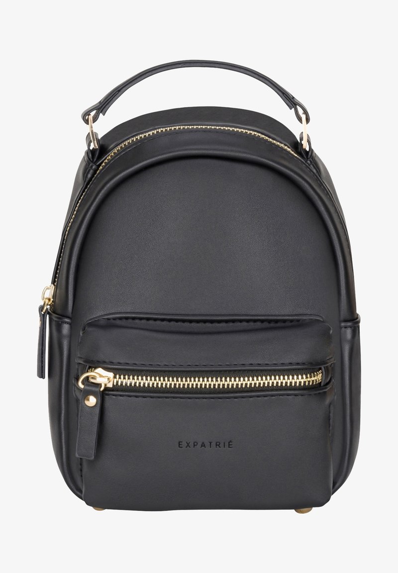 Mini sac à dos en cuir synthétique noir avec fermetures éclair dorées, poche avant, poignée supérieure, et "EXPATRIÉ" embossé sur le devant.