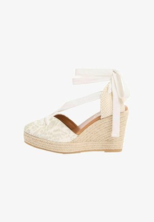 Keilabsatz-Espadrille mit beigem Stoffobermaterial mit dezentem Leopardenmuster, gewebter Jute-Sohle und Schnürung zum Wickeln um den Knöchel.