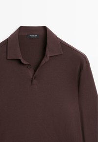 Bordeaux kleurige polo met een kraag, sluiting met twee knopen en korte mouwen. Gemaakt van zachte, gestructureerde stof. Subtiele stikdetails.