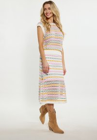 Abito a due pezzi in maglia con strisce orizzontali multicolori in rosa, verde, giallo e bianco, dal taglio rilassato. Abbinato a stivaletti alla caviglia color beige.