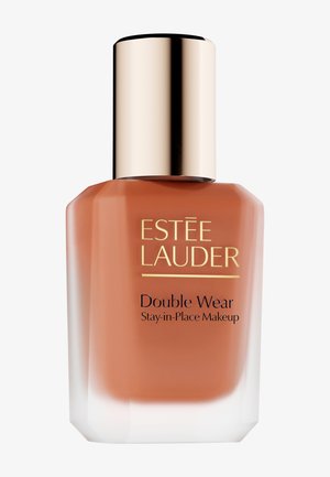 Flacon de fond de teint Estee Lauder Double Wear, forme rectangulaire, liquide ambré, bouchon doré brillant, base transparente, accents blancs, étiquette avec texte.