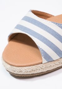 Sandale à bout ouvert avec dessus en tissu rayé bleu et blanc, semelle intérieure rembourrée couleur fauve, et détail de semelle en corde tressée.