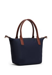 Marineblauwe tote bag met leren handvatten en accenten in bruin. Heeft een gestructureerde vorm en een ritsluiting aan de bovenkant. Gladde textuur, minimale hardware.