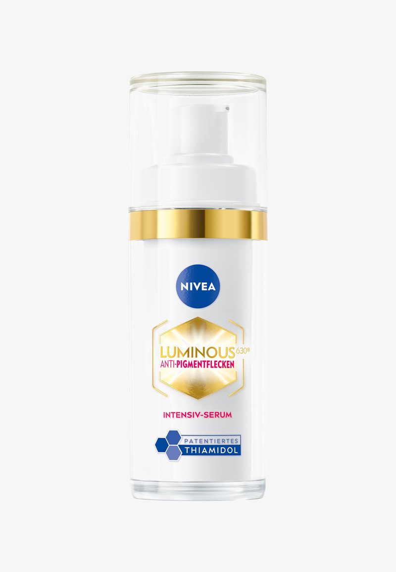 Weißer Pumpflasche mit transparentem Deckel, goldenen Akzenten und blauem Logo. Das Etikett zeigt "LUMINOUS 630® ANTI-PIGMENTFLECKEN" in Pink und sechseckigen Designs.