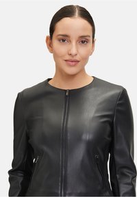 Czarna skórzana kurtka z okrągłym dekoltem, zamek błyskawiczny z przodu oraz dwie kieszenie po bokach. Gładka tekstura i dopasowany krój.
