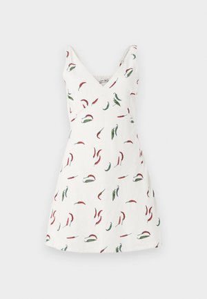 Robe blanche sans manches avec un col en V, ornée d'un motif de piments rouges et verts. Le tissu semble léger et lisse.