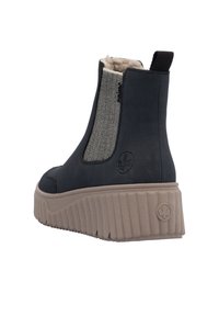 Bottine noire en cuir synthétique avec un panneau latéral élastique grise texturé et une semelle en caoutchouc épaisse présentant des rainures verticales. Une languette noire est incluse.
