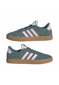 Ett par låga Adidas-sneakers i teal mocka med rosa ränder och hälflik, gummisula och en gyllene Adidas-logotyp på sidan.