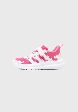 Chaussure de sport rose et blanche avec bride et lacets, avec une semelle blanche épaisse et trois bandes roses sur le côté.