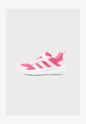 Chaussure de sport rose et blanche avec bride et lacets, avec une semelle blanche épaisse et trois bandes roses sur le côté.