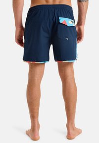 Bañadores azul marino con patrones geométricos coloridos en el dobladillo. Cintura elástica y bolsillo trasero con solapa. Tejido suave y ligero.