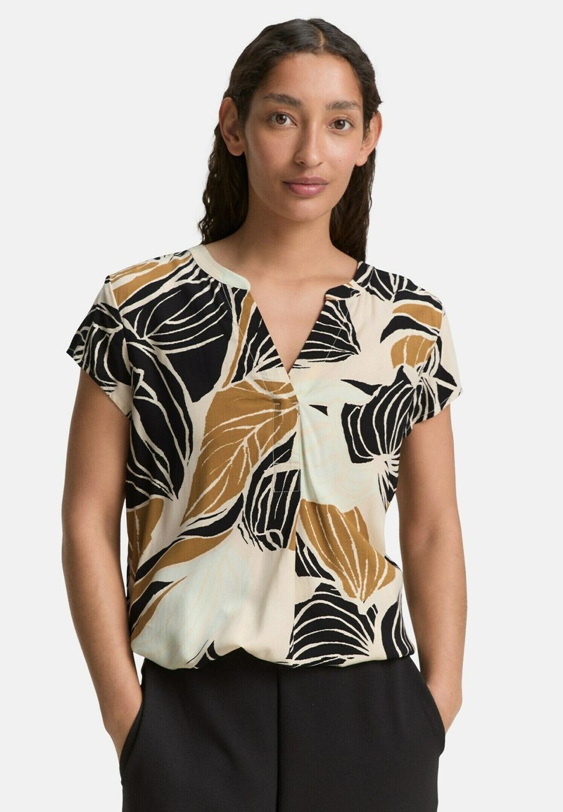 Blusa a maniche corte con scollo a V, caratterizzata da uno sfondo crema e audaci motivi di foglie nere e marroni. Realizzata in tessuto leggero.