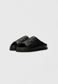 Sandale negre cu talpă deschisă, design cu vârful deschis, suprafață texturată cu modele embosate, material sintetic neted și talpă groasă.