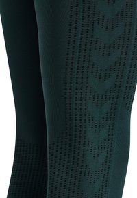 Donkergroene legging met een textuurontwerp, geometrische patronen, gaasaccenten en een gestroomlijnde, aansluitende vorm voor verbeterd comfort.