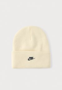 Căciulă tricotată crem cu manșetă pliată, având un logo Nike negru în față. Textură moale și design simplu cu partea superioară rotunjită.
